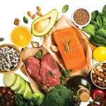 Keto diet food. Healthy food products at black background. Salmon steak, beef, beans, nuts, vegetables and olive oil. Top view image at black stone table.