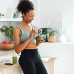 Shot of athletic woman eating a healthy fruit bowl in the kitchen at home