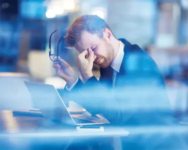 Young tired businessman sitting with his head over laptop
