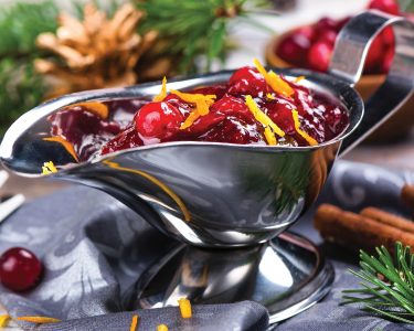 Cranberry sauce in a stainless steel sauce pan on festive christmas background