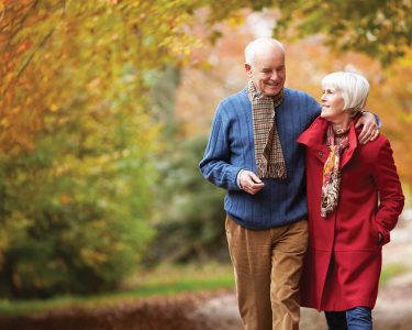 Senior Couple Walking Along Autumn Path Embracing Each Other Conversing Relationships Outdoor Caption