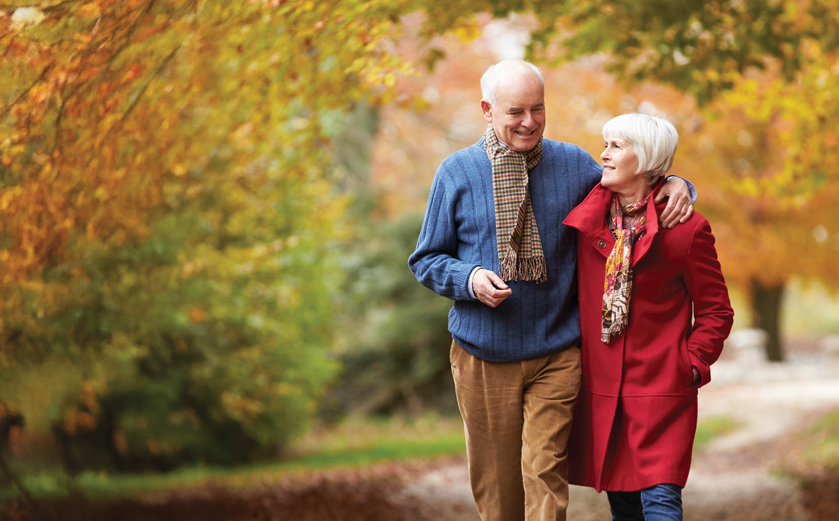 Senior Couple Walking Along Autumn Path Embracing Each Other Conversing Relationships Outdoor Caption
