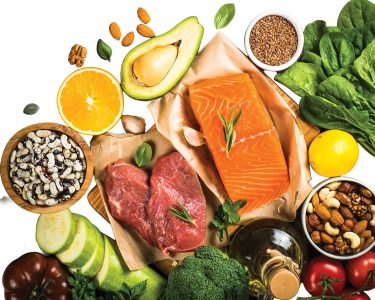 Keto diet food. Healthy food products at black background. Salmon steak, beef, beans, nuts, vegetables and olive oil. Top view image at black stone table.