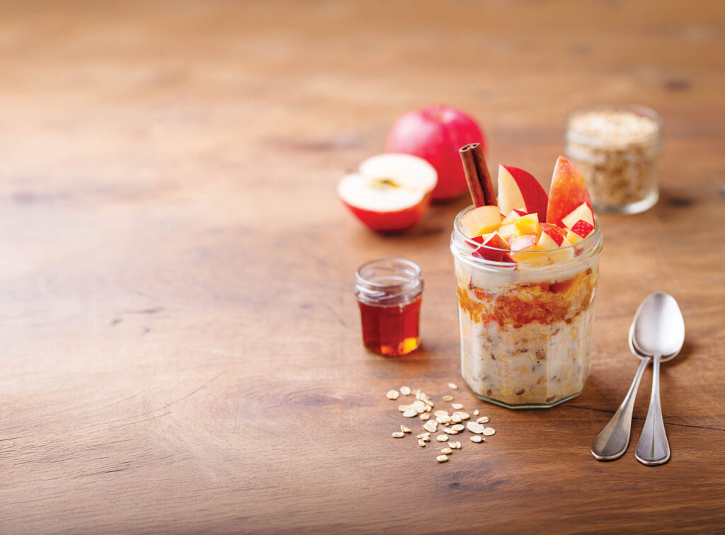 Overnight oats, bircher muesli with apple, cinnamon and honey. Wooden background. Copy space.