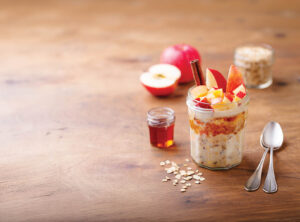 Overnight oats, bircher muesli with apple, cinnamon and honey. Wooden background. Copy space.