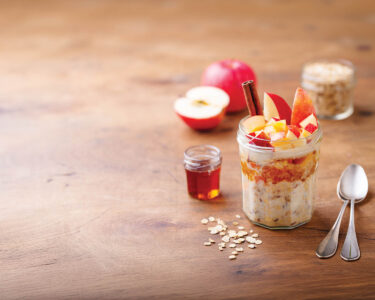 Overnight oats, bircher muesli with apple, cinnamon and honey. Wooden background. Copy space.