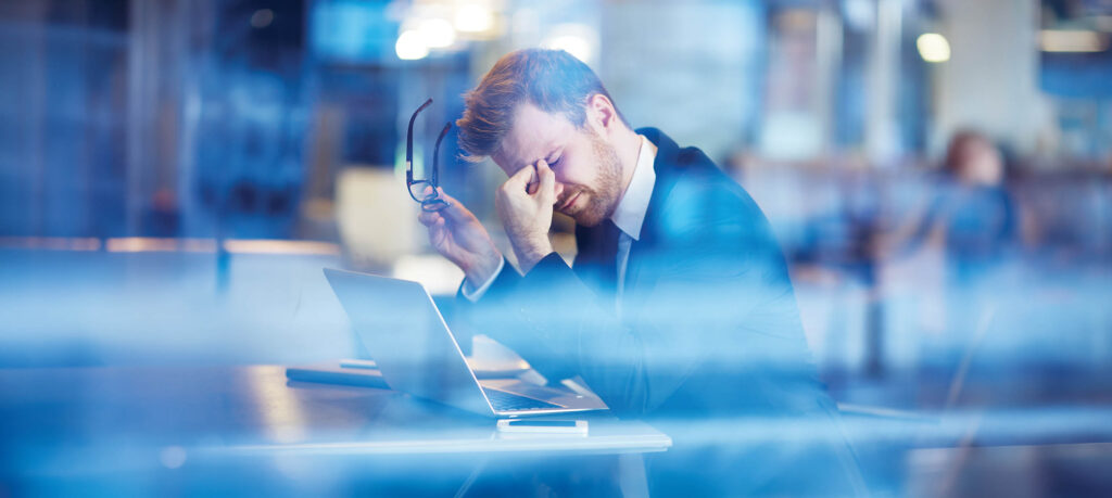 Young tired businessman sitting with his head over laptop
